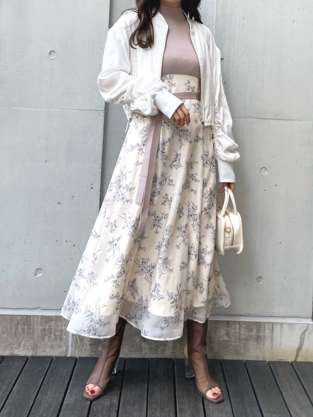 ブラック系のブーツ、ブラック系のハンドバッグ、ホワイト系のワンピースを着用したレディースの春コーディネートの3枚目の写真