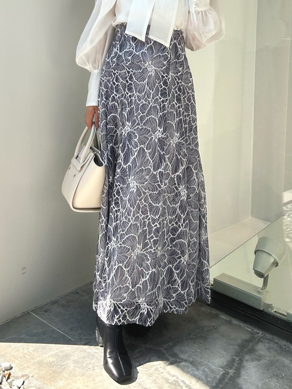 ブラック系のライダースジャケット、ホワイト系のシャツ/ブラウス、ブルー系のスカートを着用したレディースの夏コーディネートの9枚目の写真