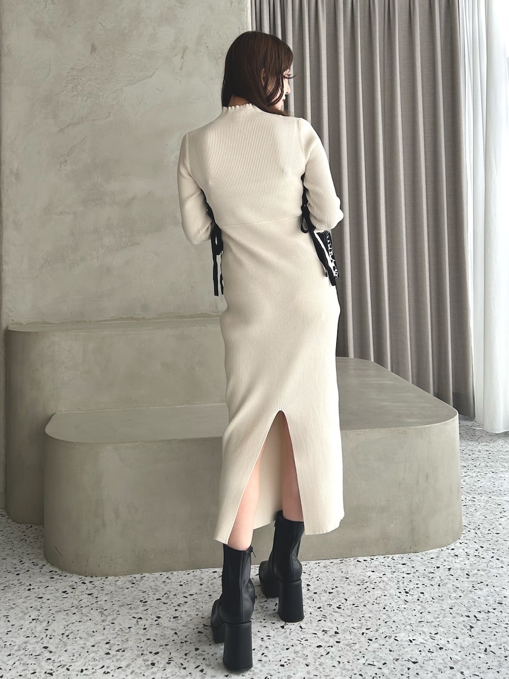 ホワイト系のワンピース、ブラック系のブーツ、ブラック系のハンドバッグを着用したレディースの冬コーディネートの2枚目の写真