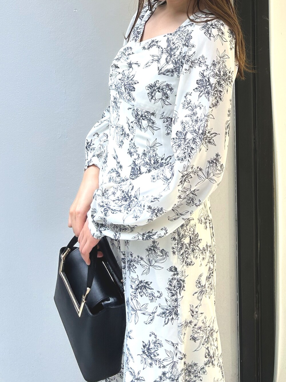 ブラック系のハンドバッグ、ホワイト系のワンピースを着用したレディースの夏コーディネートの3枚目の写真