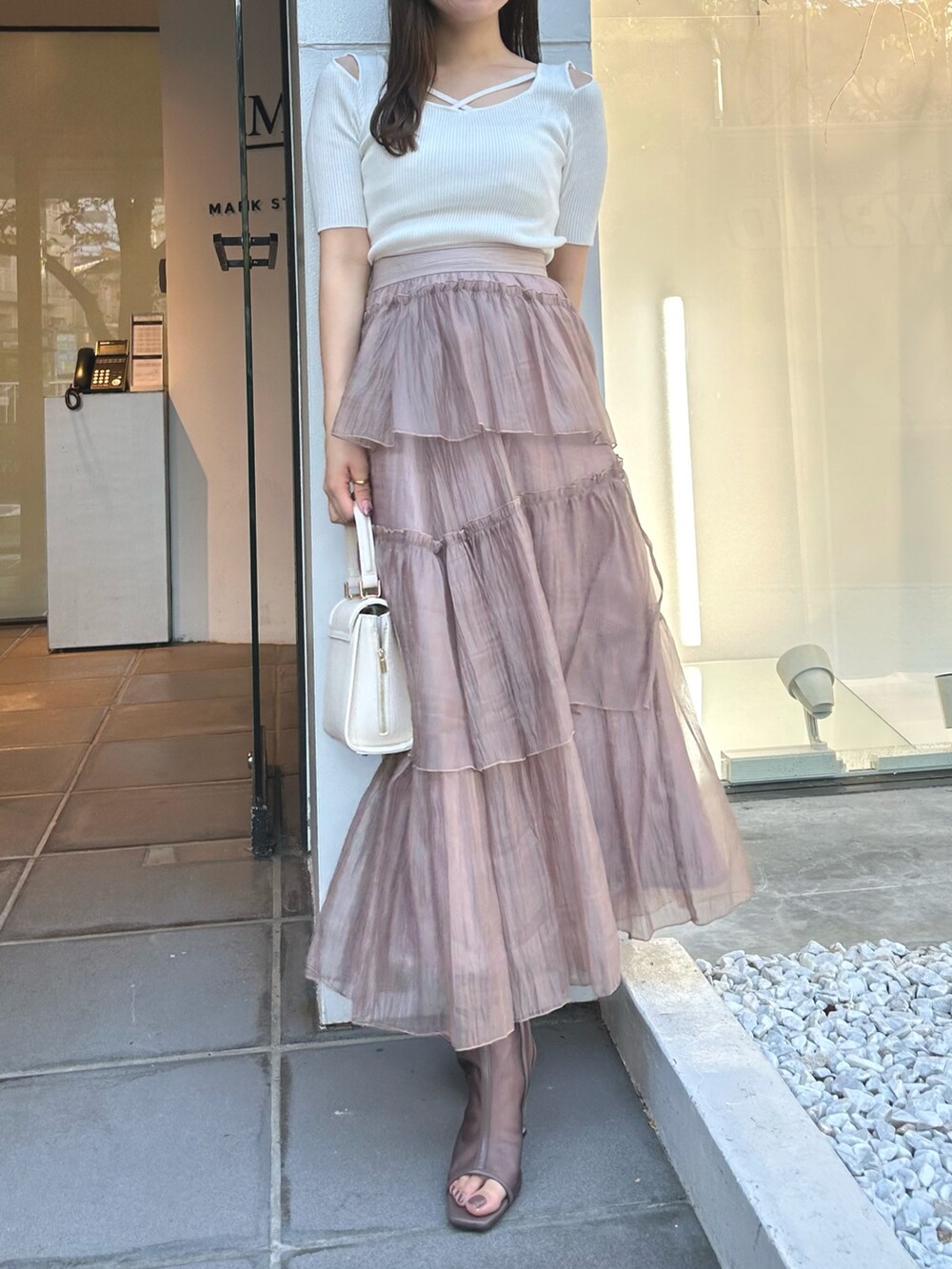 ホワイト系のニット/セーター、ブラウン系のスカート、ホワイト系のショルダーバッグを着用したレディースの冬コーディネートの3枚目の写真