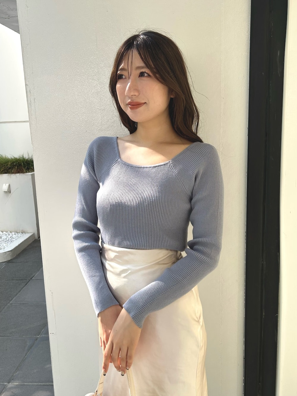 ブルー系のニット/セーター、ホワイト系のスカート、ブラック系のブーツを着用したレディースの秋コーディネートの5枚目の写真