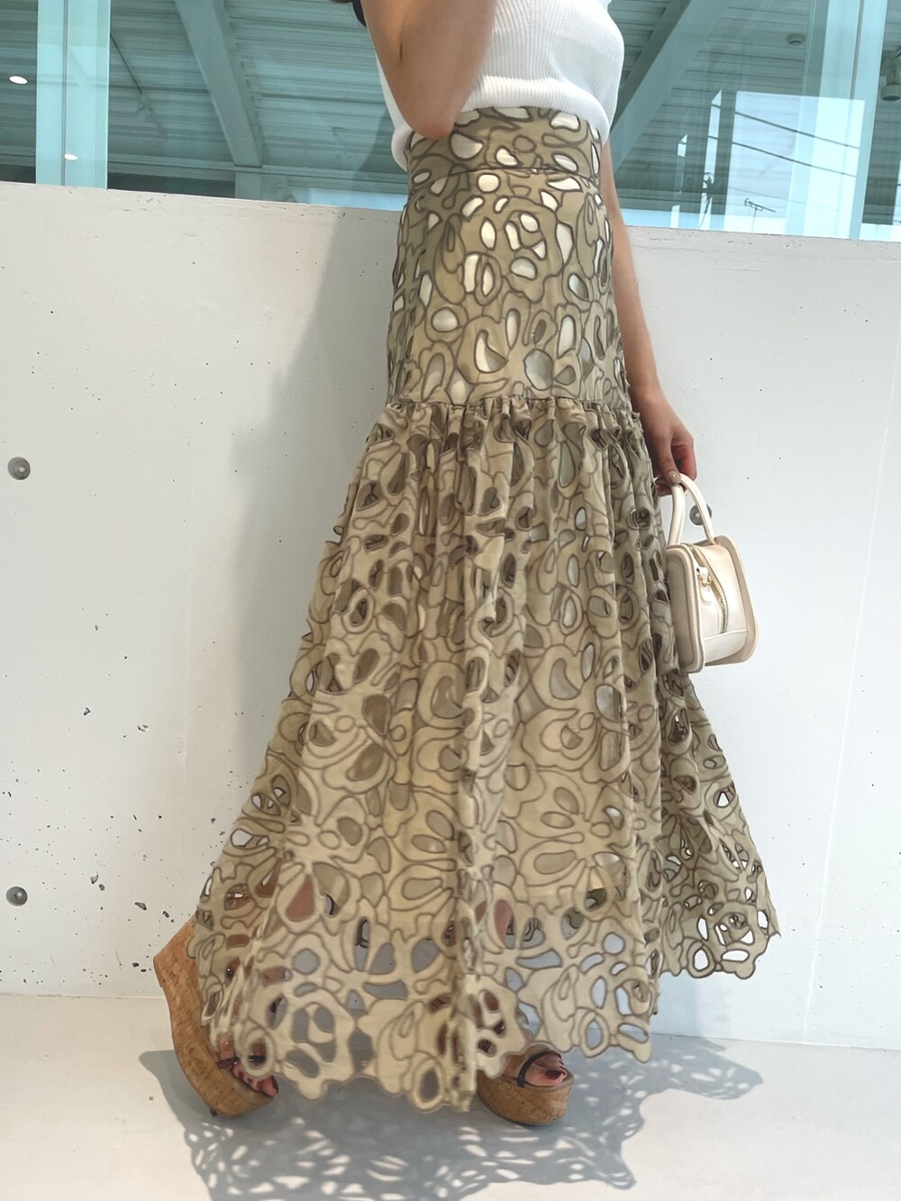 ホワイト系のニット/セーター、ブラウン系のサンダル、イエロー系のスカートを着用したレディースの春コーディネートの6枚目の写真