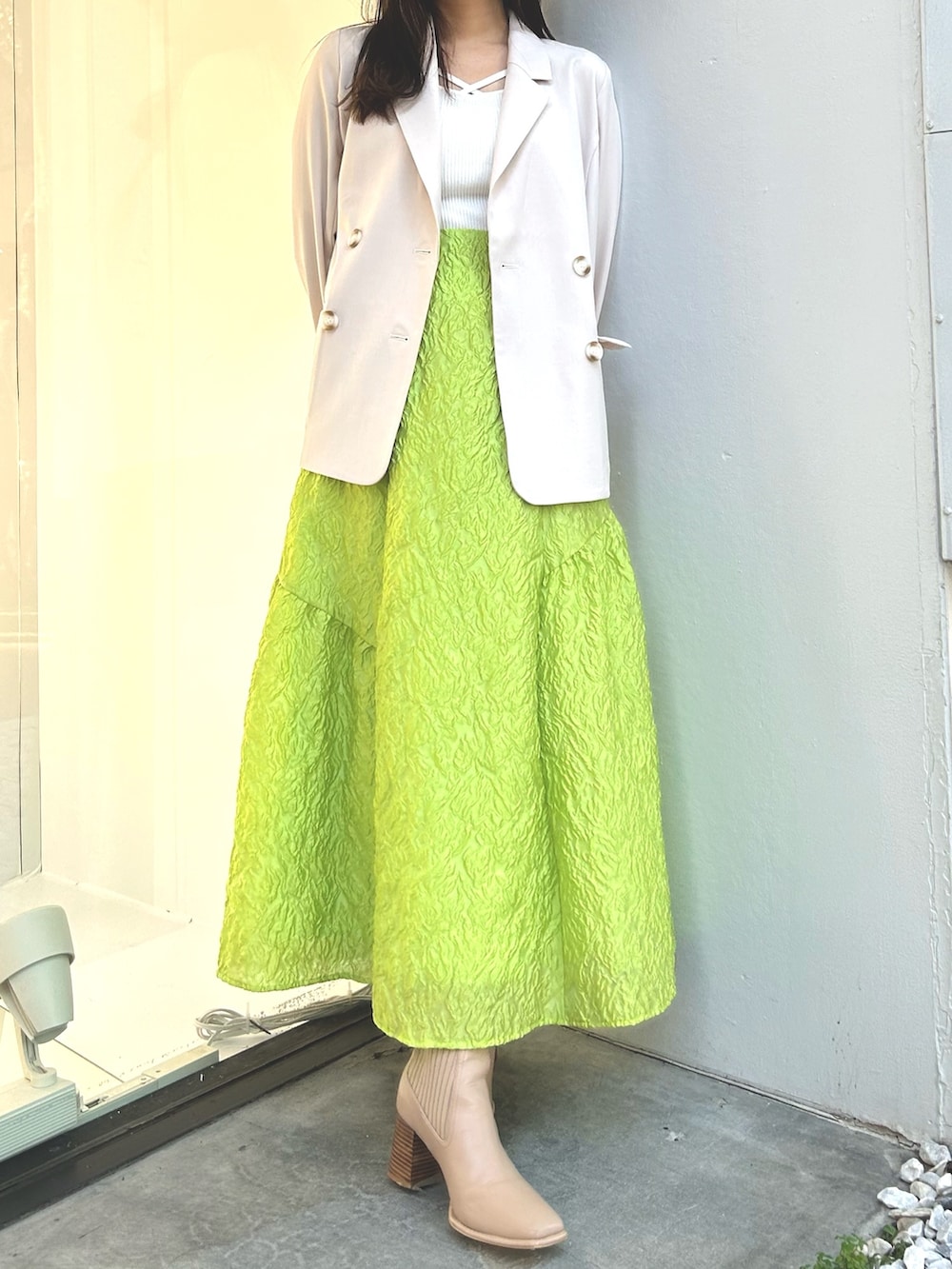 ホワイト系のニット/セーター、ホワイト系のテーラードジャケット、グリーン系のスカートを着用したレディースの春コーディネートの4枚目の写真