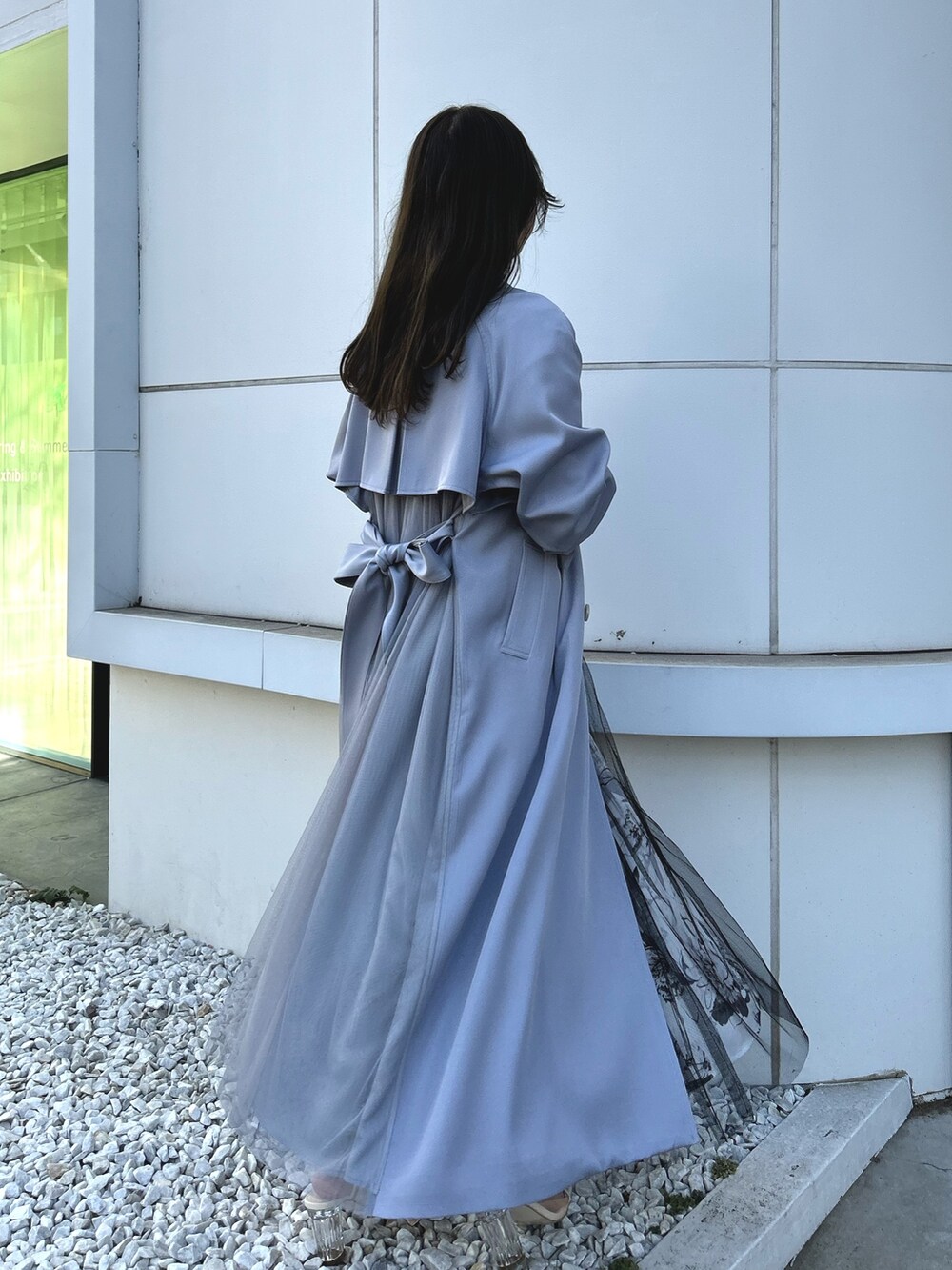 ブルー系のトレンチコート、ブラック系のワンピース、ホワイト系のブーツを着用したレディースの冬コーディネートの5枚目の写真