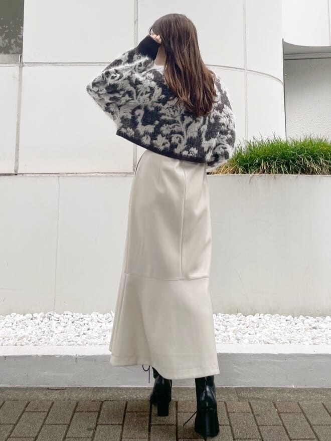 ブラウン系のニット/セーター、ブラック系のブーツ、ホワイト系のスカートを着用したレディースの秋コーディネートの3枚目の写真