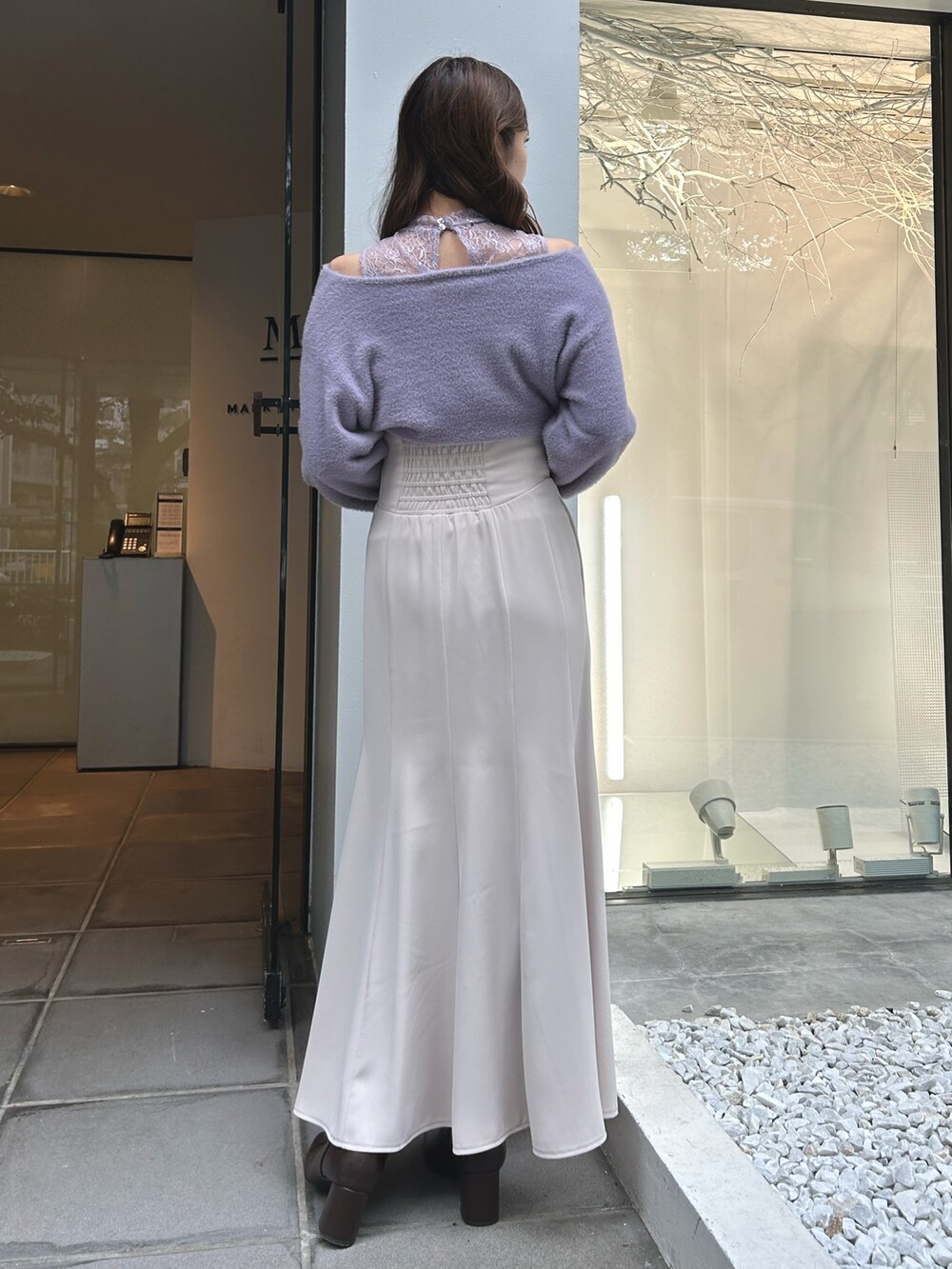 パープル系のニット/セーター、ホワイト系のスカート、ブラック系のショルダーバッグを着用したレディースの冬コーディネートの3枚目の写真