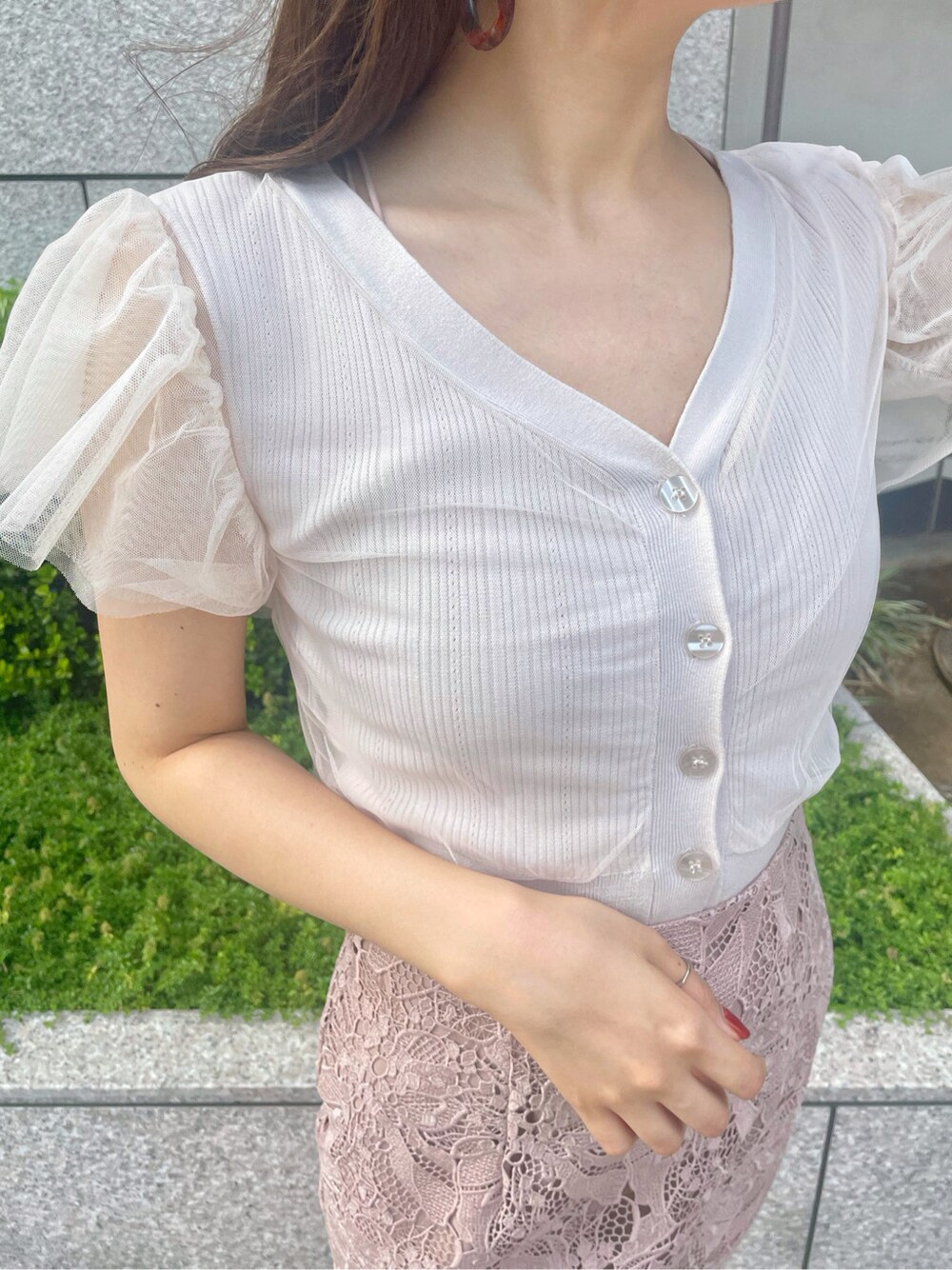 ベージュ系のスカート、ホワイト系のニット/セーターを着用したレディースの春コーディネートの3枚目の写真