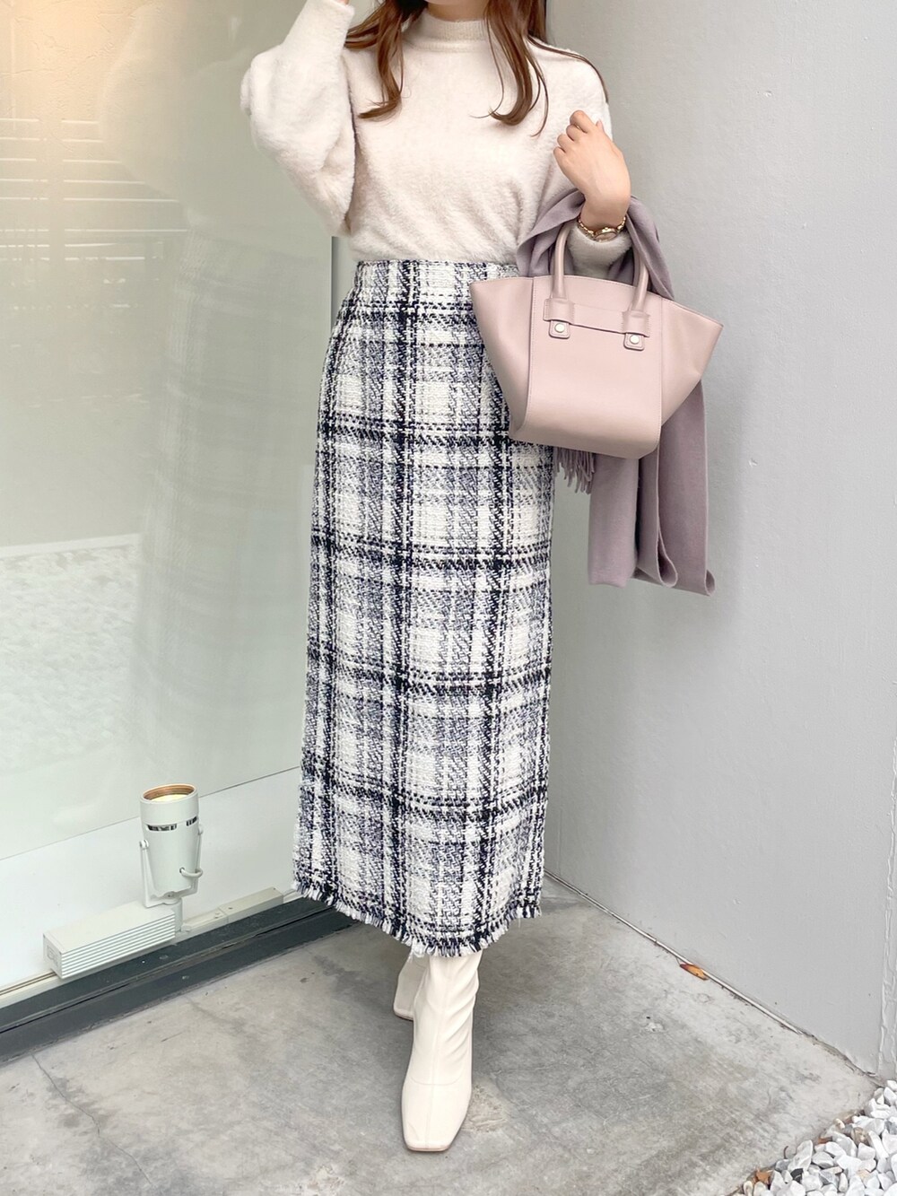 ホワイト系のチェスターコート、ホワイト系のニット/セーター、ベージュ系のハンドバッグを着用したレディースの冬コーディネートの3枚目の写真
