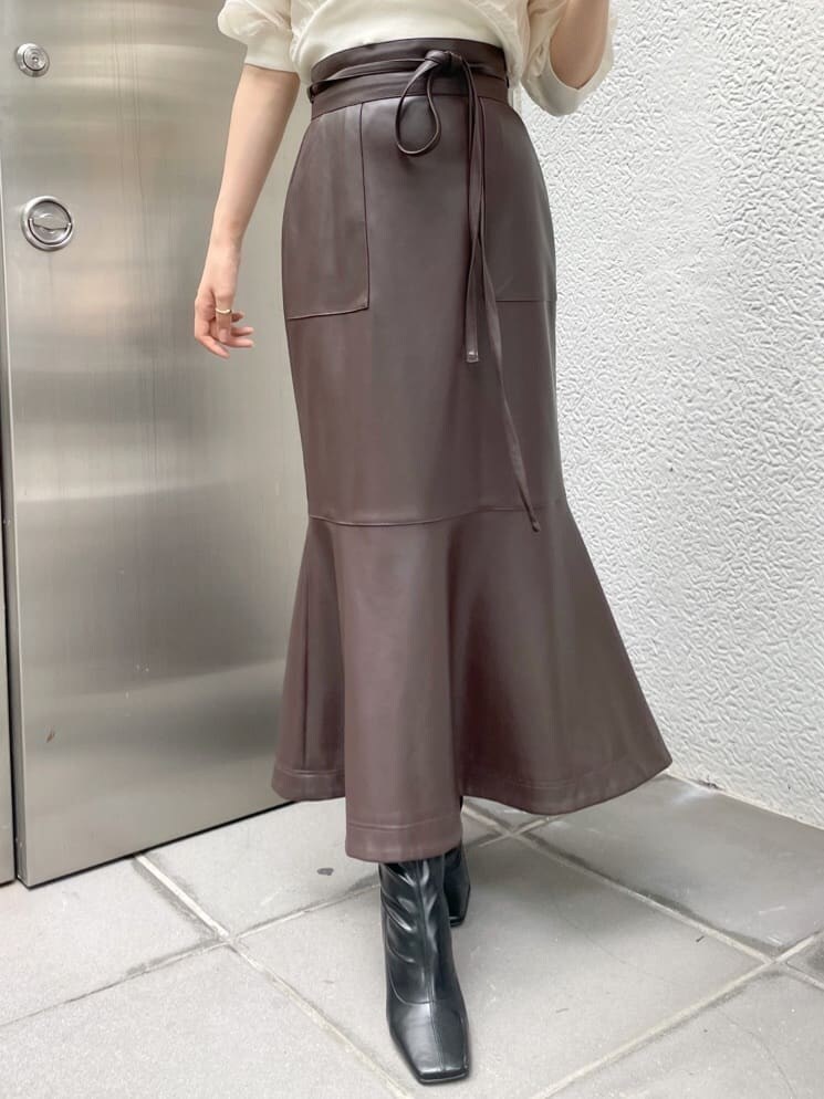 ブラック系のブーツ、ブラウン系のスカート、ホワイト系のニット/セーターを着用したレディースの夏コーディネートの5枚目の写真