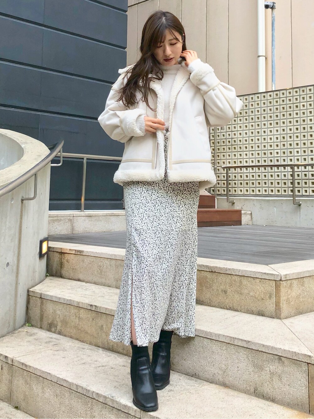 ホワイト系のニット/セーター、ホワイト系のムートンコート、ホワイト系のスカートを着用したレディースの冬コーディネートの2枚目の写真