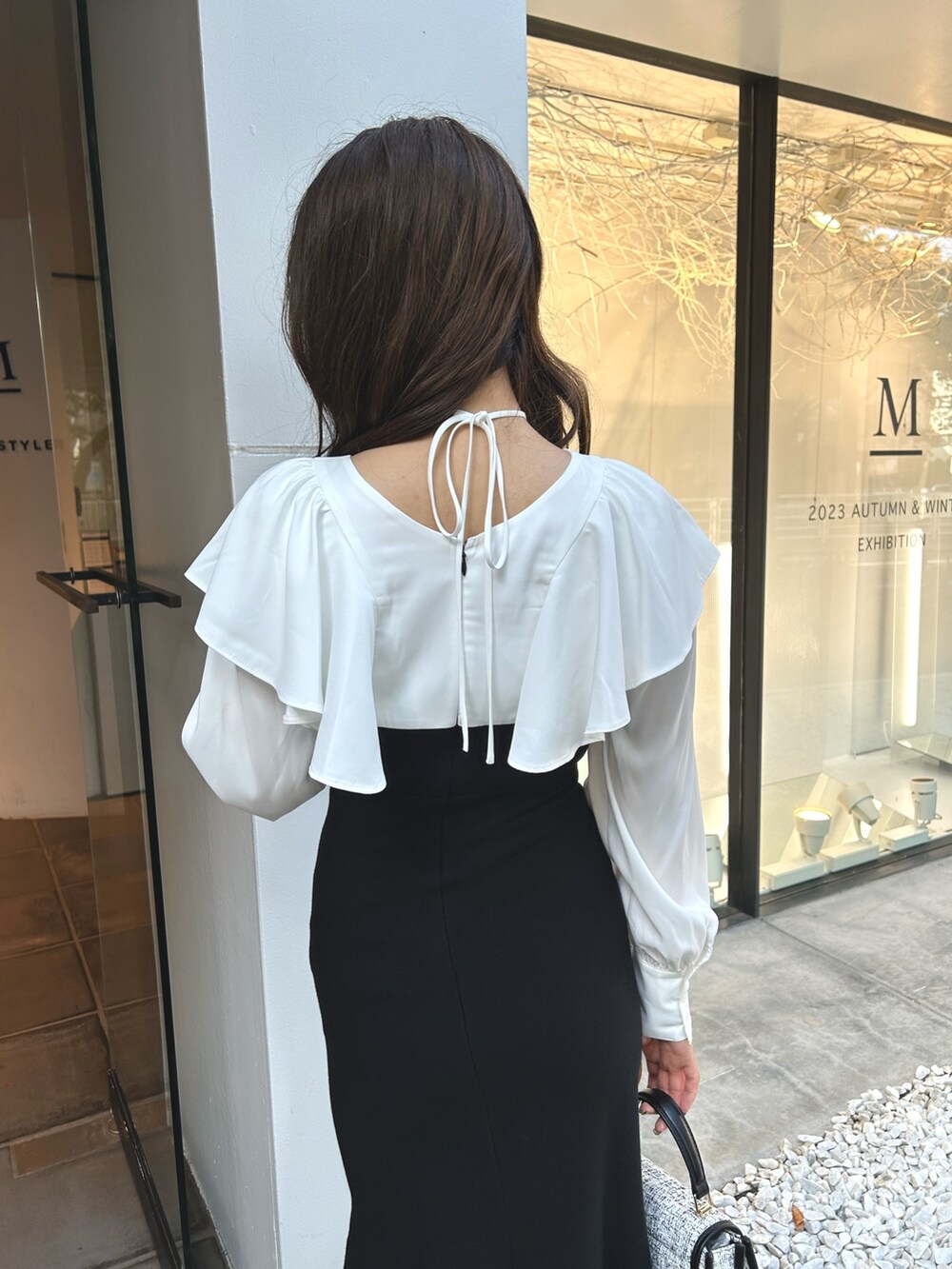 ブラック系のワンピース、ブラック系のショルダーバッグ、ブラック系のブーツを着用したレディースの秋コーディネートの6枚目の写真