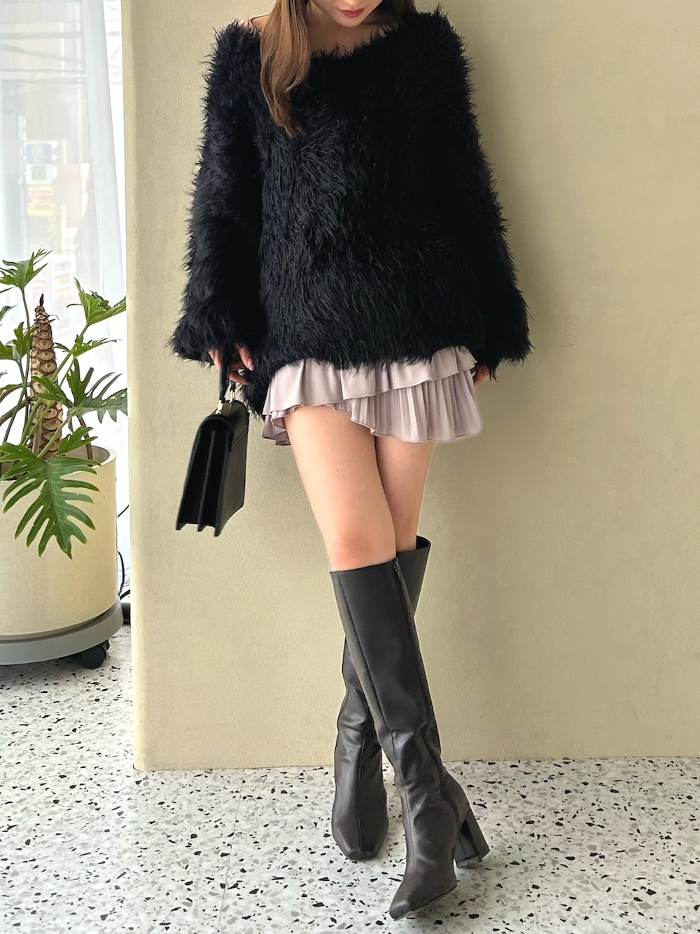 ピンク系のスカート、ブラック系のニット/セーター、ブラウン系のブーツを着用したレディースの冬コーディネートの2枚目の写真