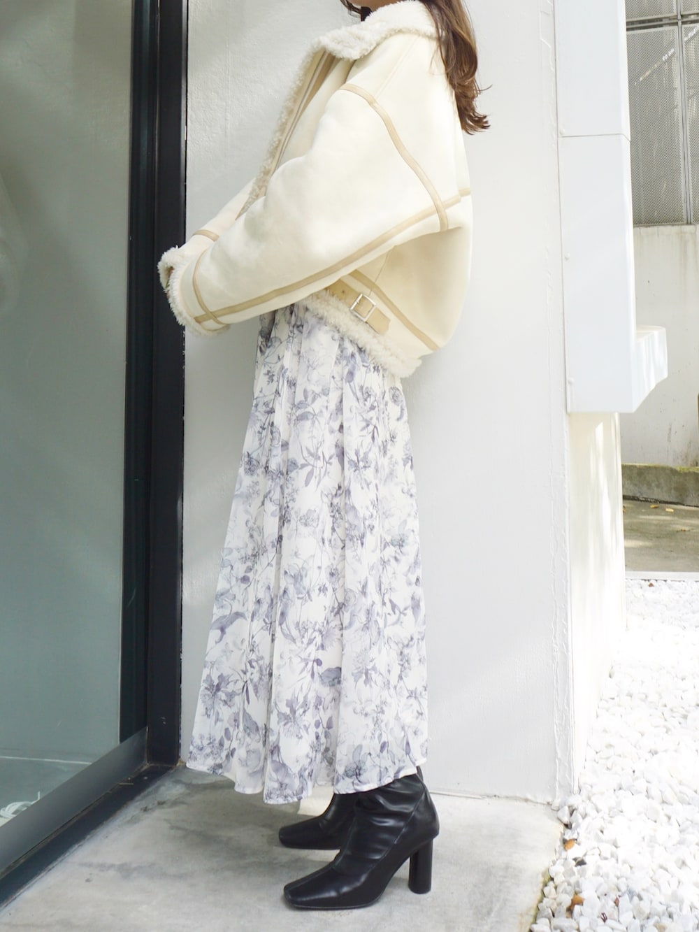 ブラック系のブーツ、ホワイト系のムートンコート、グレー系のワンピースを着用したレディースの冬コーディネートの5枚目の写真