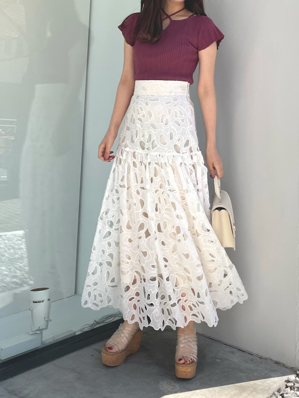 ピンク系のニット/セーター、ホワイト系のハンドバッグ、ホワイト系のスカートを着用したレディースの春コーディネートの2枚目の写真