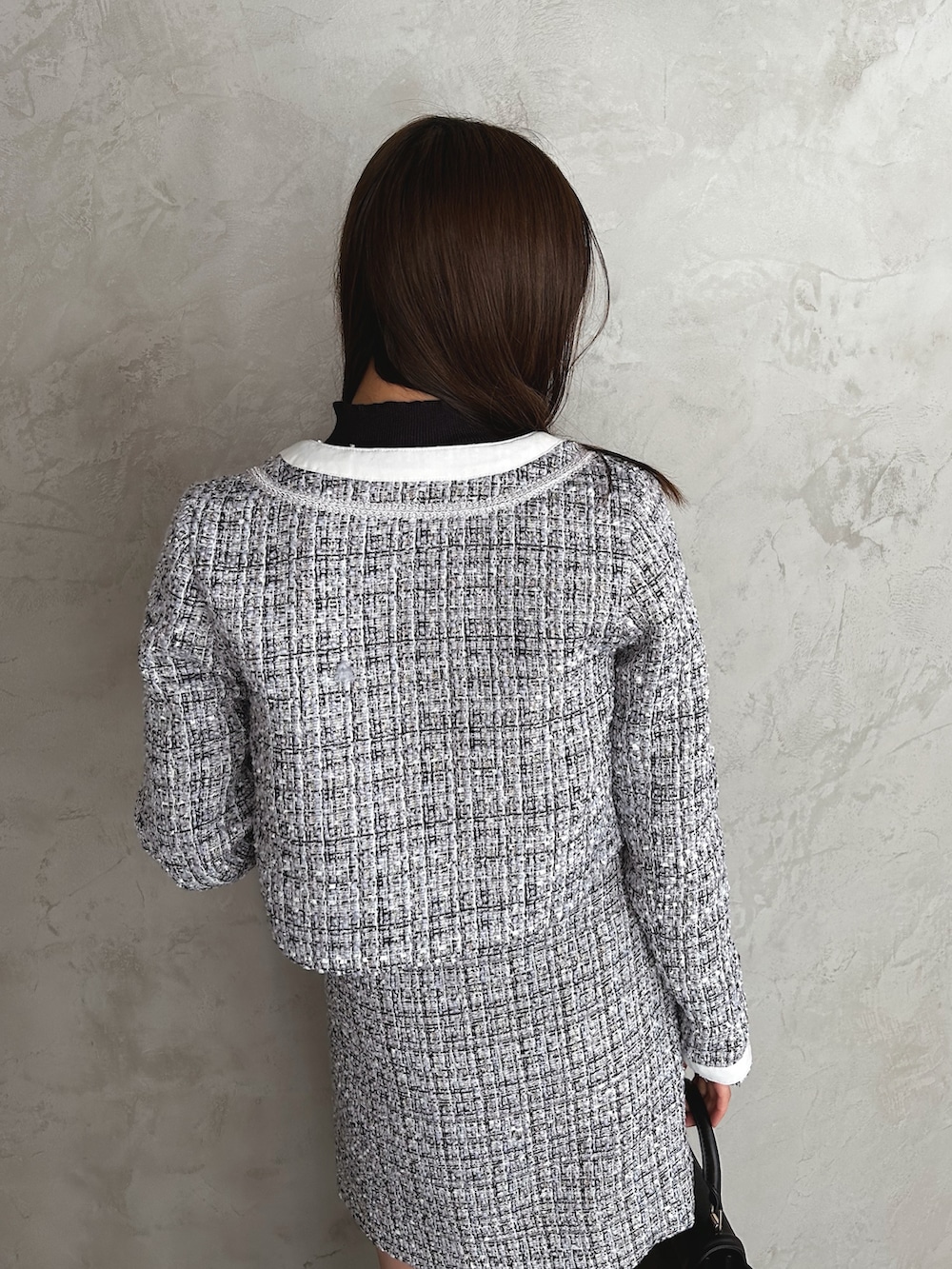 ホワイト系のノーカラージャケット、ホワイト系のスカート、ブラック系のニット/セーターを着用したレディースの秋コーディネートの5枚目の写真