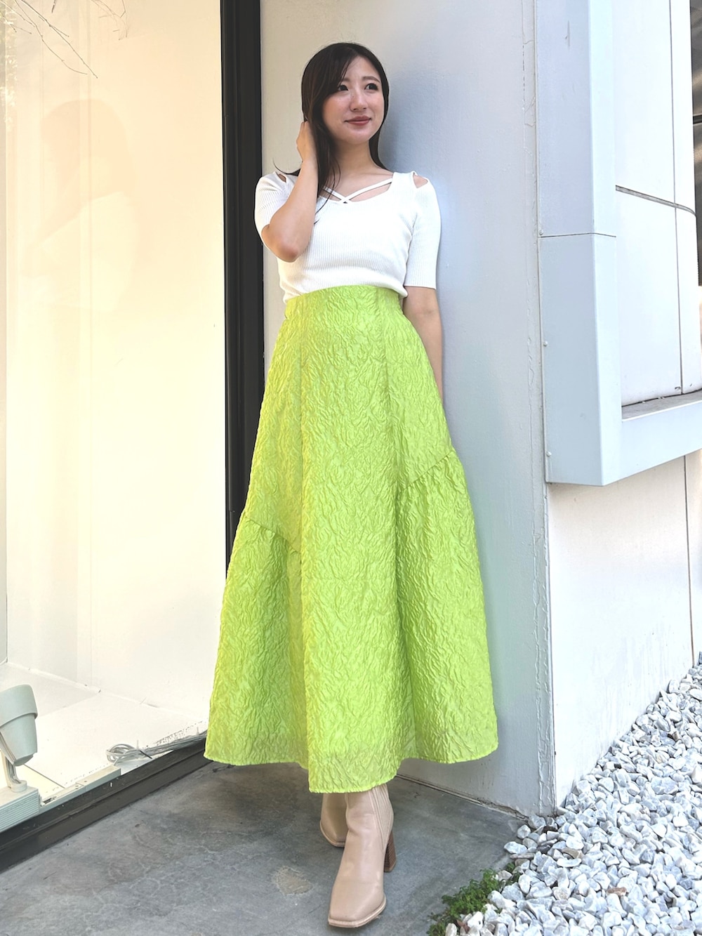 ホワイト系のニット/セーター、ホワイト系のテーラードジャケット、グリーン系のスカートを着用したレディースの春コーディネートの2枚目の写真