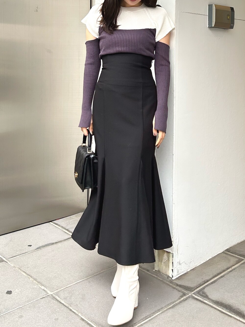 グレー系のニット/セーター、ブラック系のスカート、ブラック系のショルダーバッグを着用したレディースの冬コーディネートの2枚目の写真