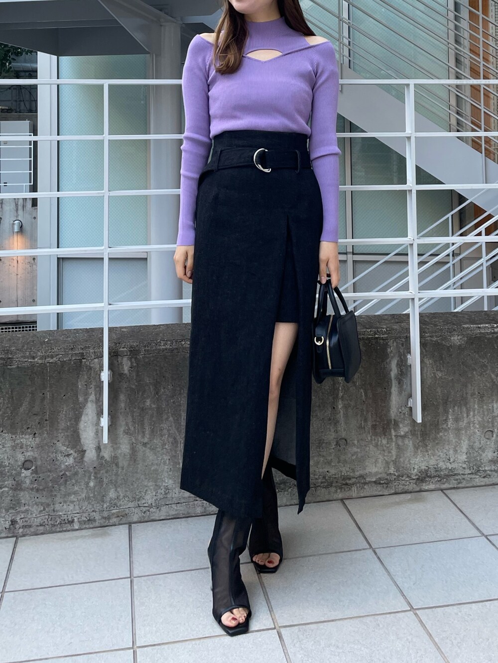 パープル系のニット/セーター、ブラック系のハンドバッグ、ブラック系のスカートを着用したレディースの冬コーディネートの2枚目の写真