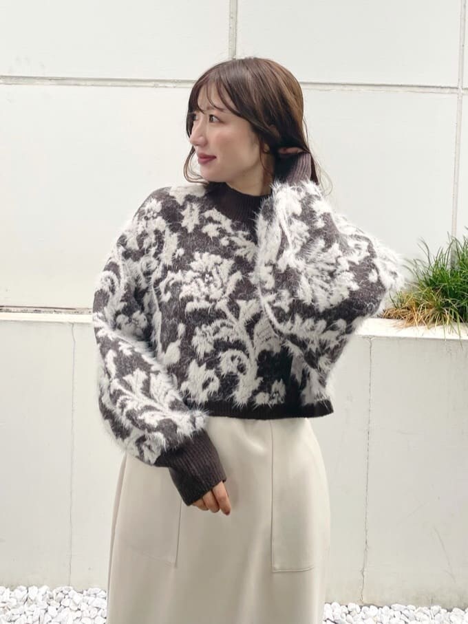 ブラウン系のニット/セーター、ブラック系のブーツ、ホワイト系のスカートを着用したレディースの秋コーディネートの4枚目の写真