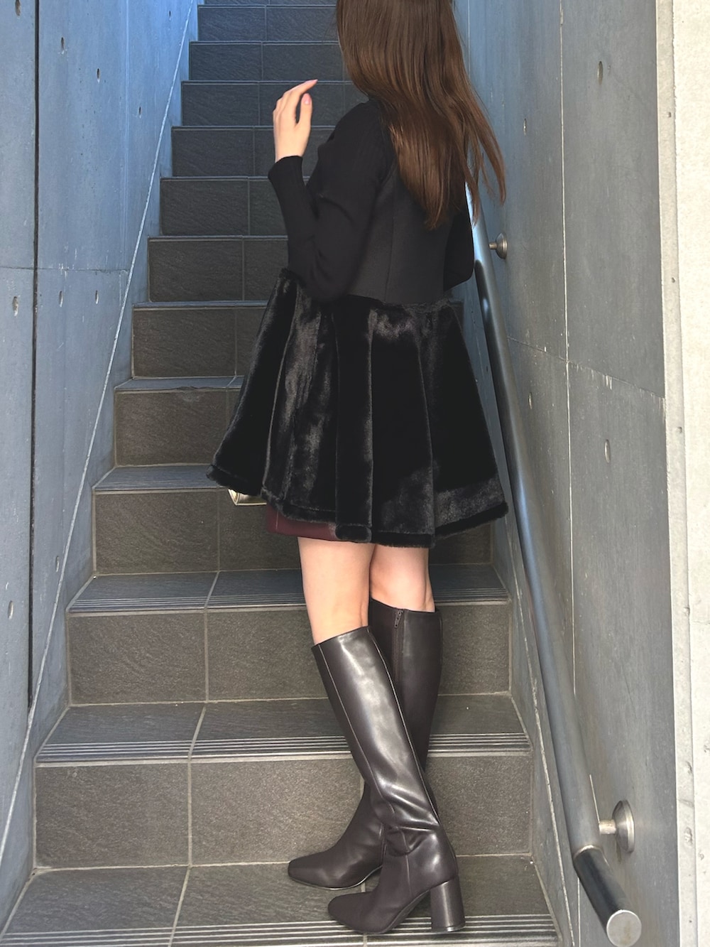 ブラック系のワンピース、レッド系のスカート、ブラウン系のブーツを着用したレディースの秋コーディネートの3枚目の写真