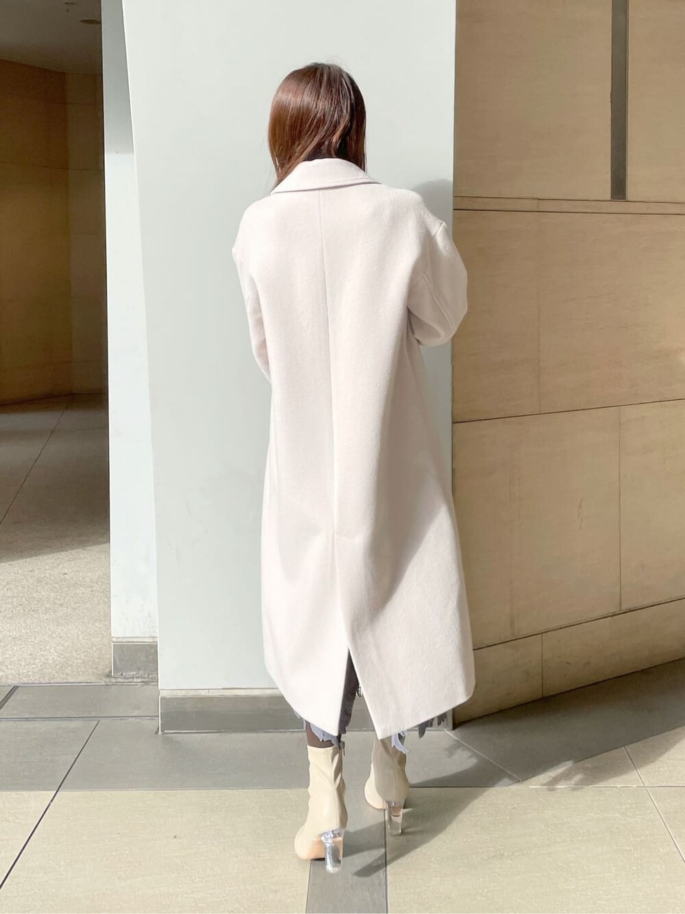 ホワイト系のチェスターコート、ホワイト系のニット/セーター、ブルー系のスカートを着用したレディースの冬コーディネートの3枚目の写真