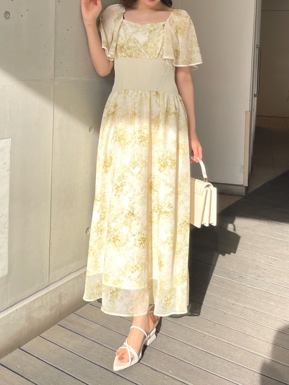 ホワイト系のハンドバッグ、イエロー系のワンピース、ホワイト系のサンダルを着用したレディースの春コーディネートの3枚目の写真