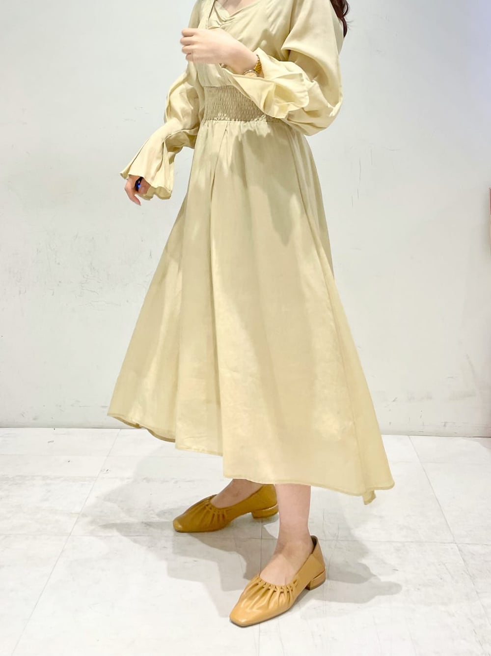 イエロー系のワンピース、ブラウン系のパンプスを着用したレディースの冬コーディネートの6枚目の写真