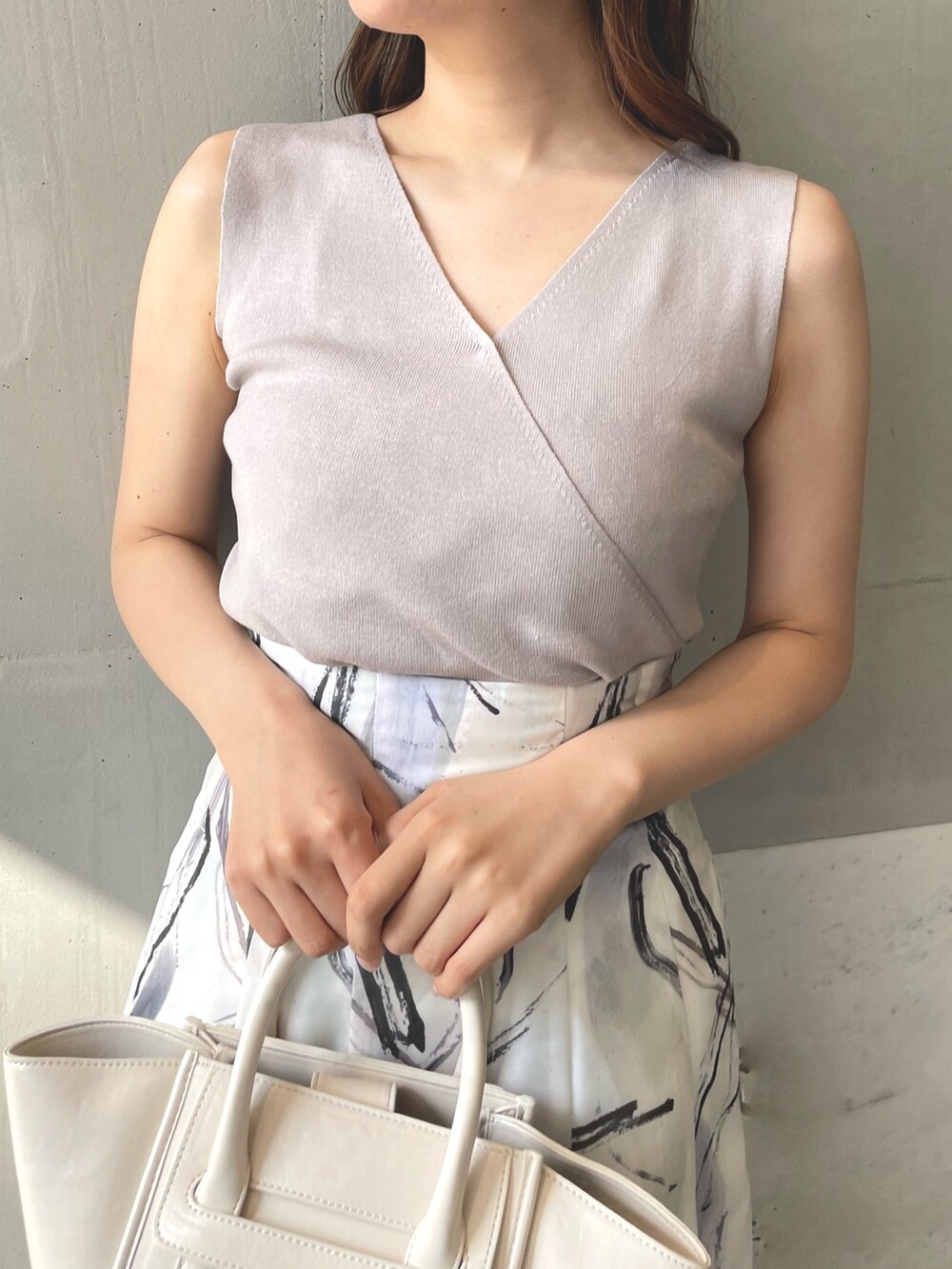 ピンク系のニット/セーター、グレー系のスカート、ホワイト系のトートバッグを着用したレディースの春コーディネートの3枚目の写真