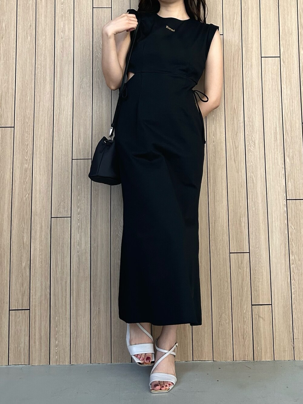 ブラック系のショルダーバッグ、ベージュ系のサンダル、ブラック系のワンピースを着用したレディースの春コーディネートの2枚目の写真