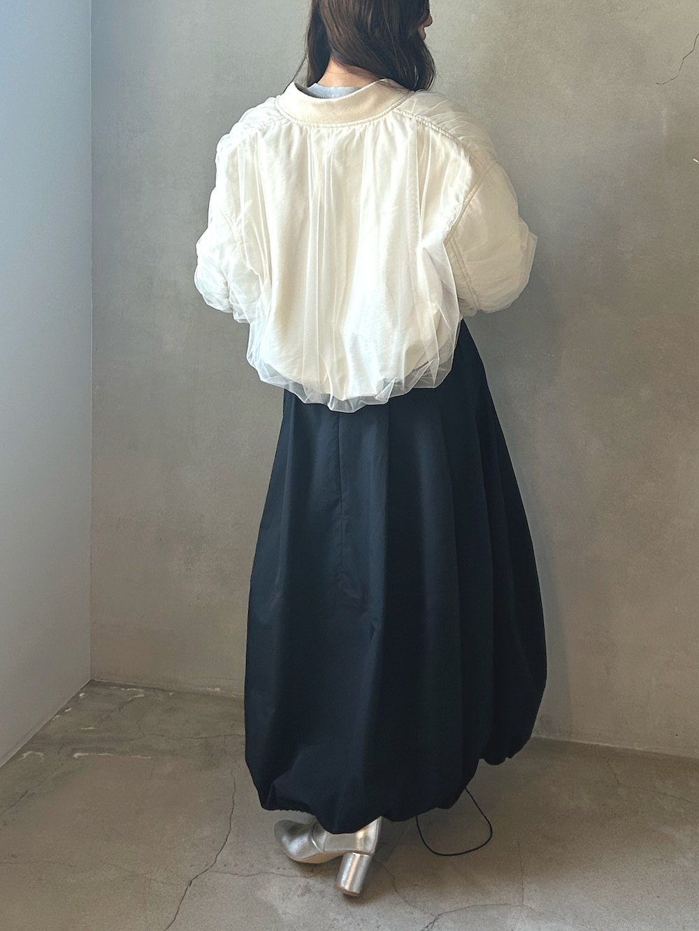 グレー系のニット/セーター、ホワイト系のMA-1、ブラック系のスカートを着用したレディースの春コーディネートの2枚目の写真