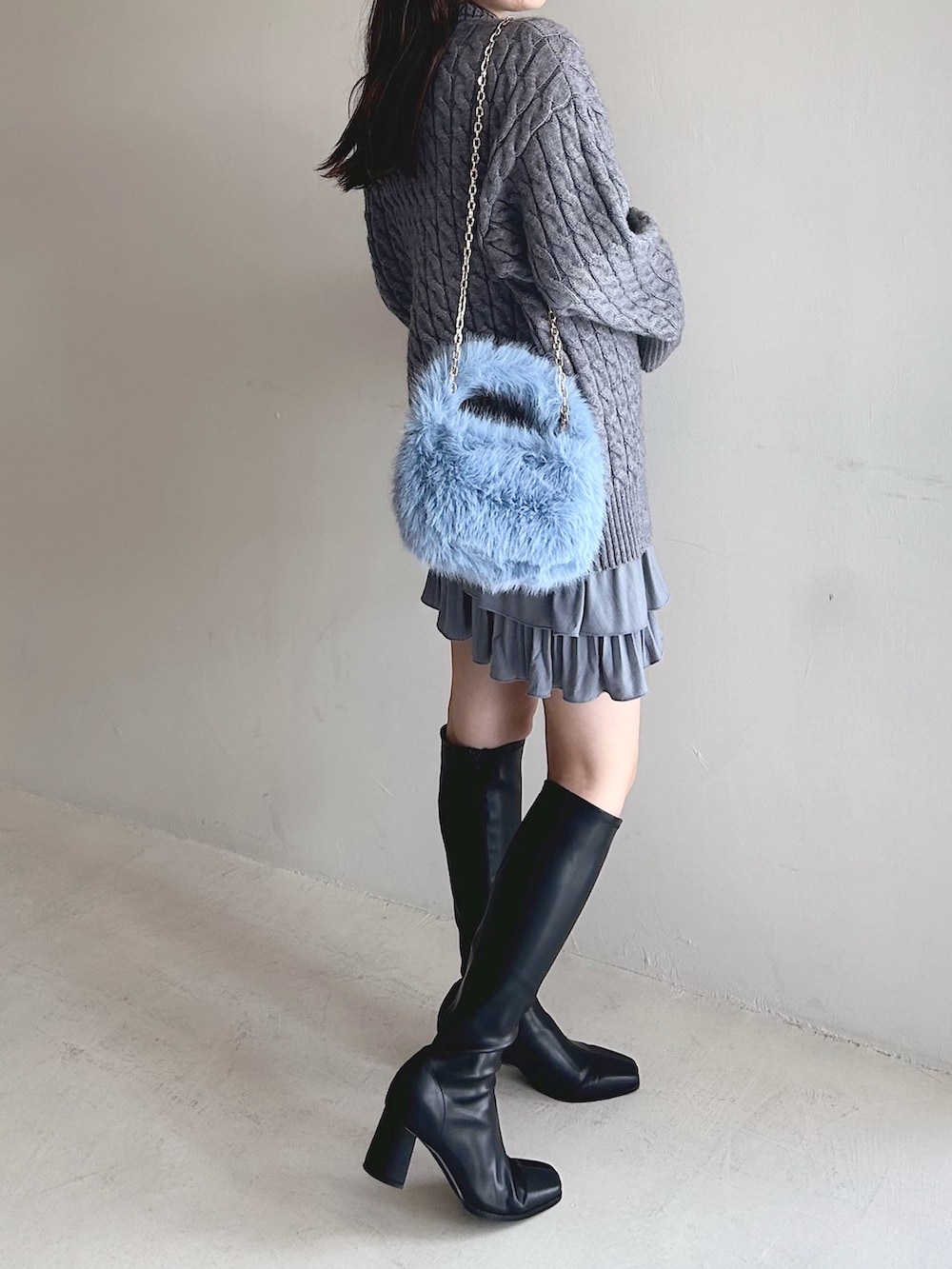 グレー系のニット/セーター、ブルー系のハンドバッグ、ブラック系のブーツを着用したレディースの冬コーディネートの3枚目の写真