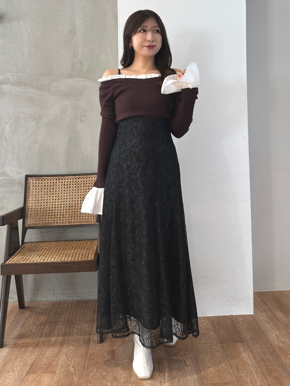 ブラウン系のニット/セーター、ブラック系のスカート、ホワイト系のブーツを着用したレディースの秋コーディネートの2枚目の写真