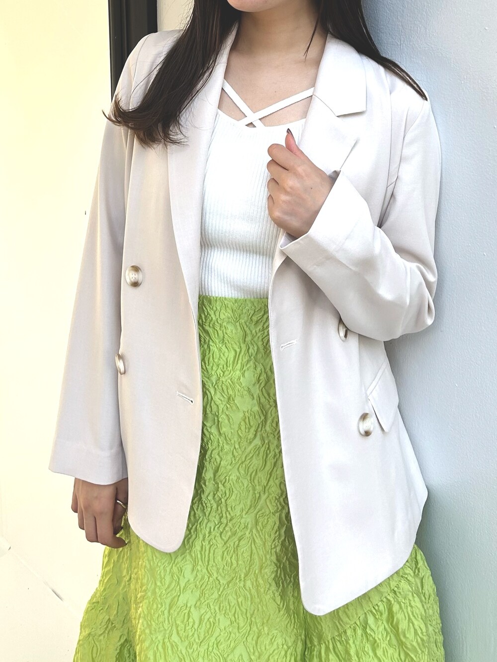 ホワイト系のニット/セーター、ホワイト系のテーラードジャケット、グリーン系のスカートを着用したレディースの春コーディネートの7枚目の写真