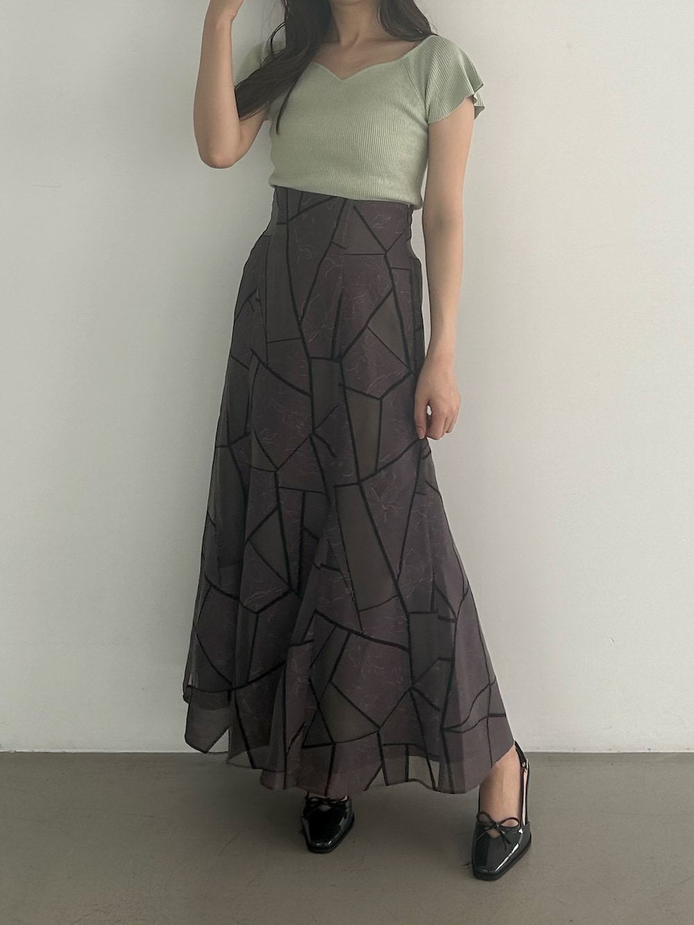 グリーン系のニット/セーター、ブラウン系のスカート、グレー系のパンプスを着用したレディースの夏コーディネートの3枚目の写真