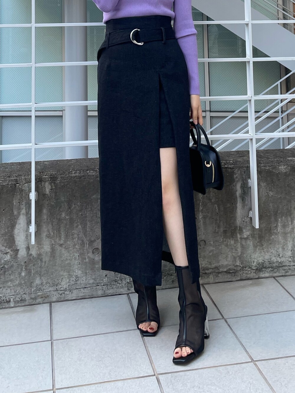 パープル系のニット/セーター、ブラック系のハンドバッグ、ブラック系のスカートを着用したレディースの冬コーディネートの4枚目の写真