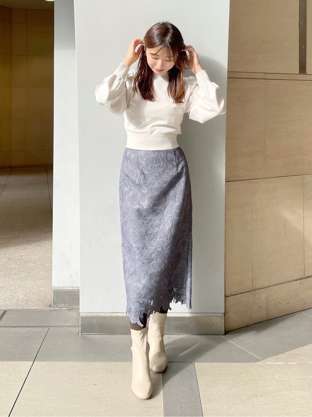 ホワイト系のチェスターコート、ホワイト系のニット/セーター、ブルー系のスカートを着用したレディースの冬コーディネートの4枚目の写真