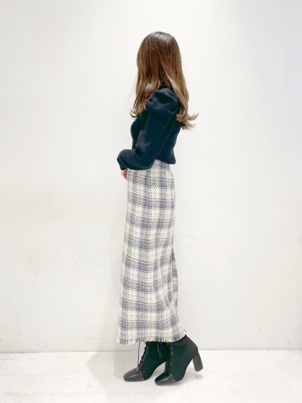 ブラック系のブーツ、ブルー系のスカート、ブラック系のニット/セーターを着用したレディースの冬コーディネートの2枚目の写真