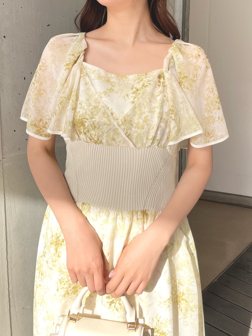 ホワイト系のハンドバッグ、イエロー系のワンピース、ホワイト系のサンダルを着用したレディースの春コーディネートの5枚目の写真