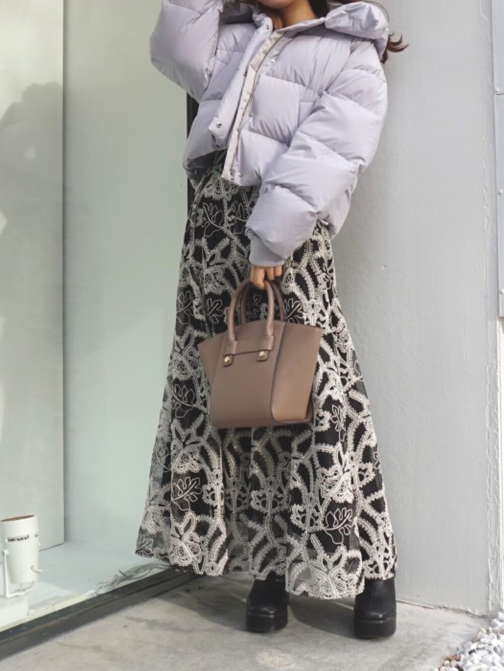 ブラック系のブーツ、ベージュ系のハンドバッグ、ブラック系のスカートを着用したレディースの冬コーディネートの3枚目の写真