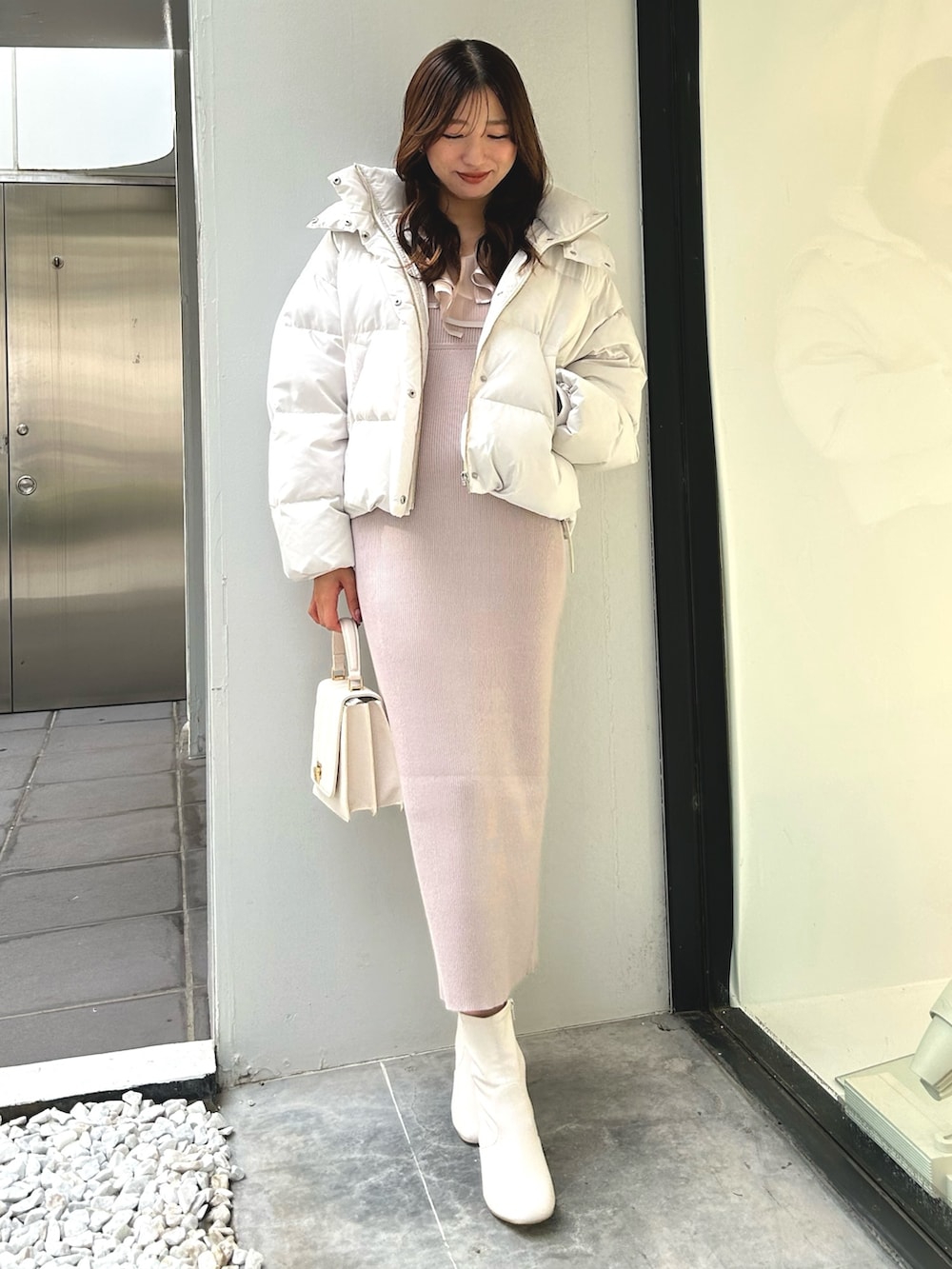 ピンク系のワンピース、ホワイト系のショルダーバッグ、ホワイト系のダウンジャケット/コートを着用したレディースの冬コーディネートの2枚目の写真