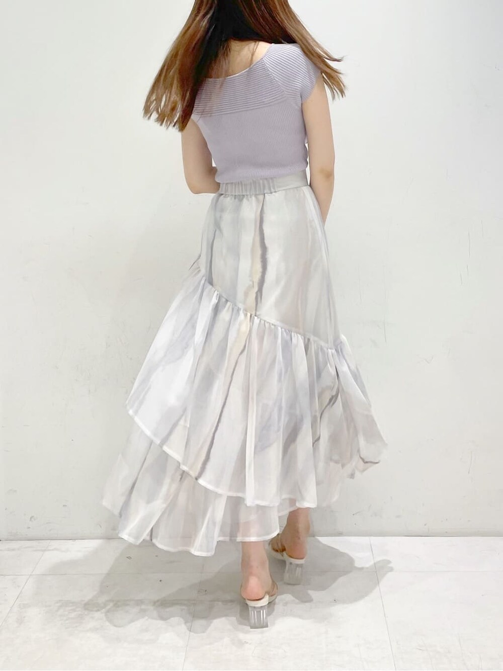 ピンク系のスカート、ベージュ系のサンダル、パープル系のニット/セーターを着用したレディースの春コーディネートの4枚目の写真