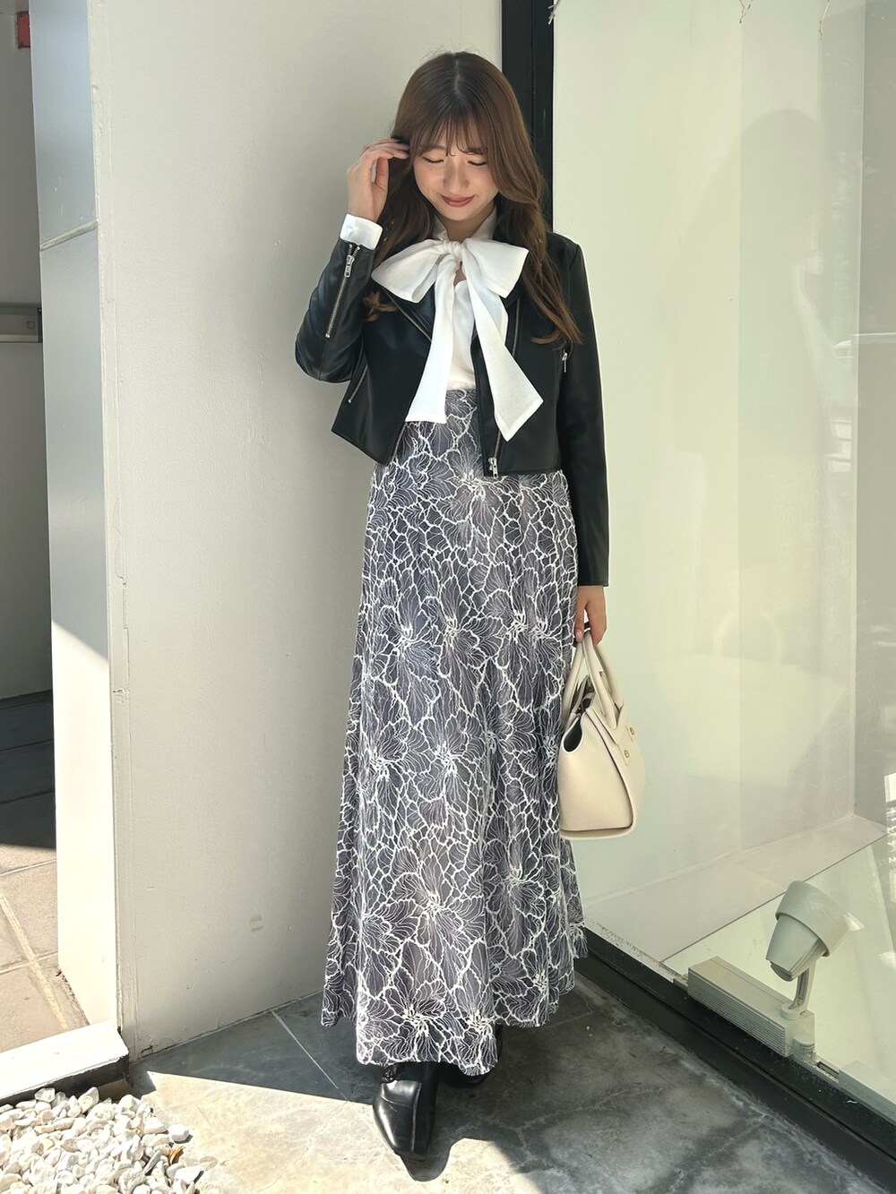 ブラック系のライダースジャケット、ホワイト系のシャツ/ブラウス、ブルー系のスカートを着用したレディースの夏コーディネートの2枚目の写真