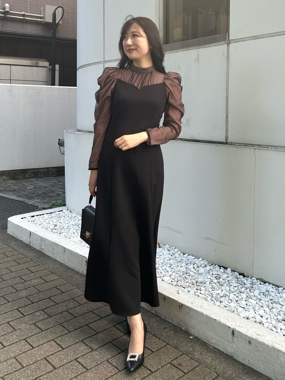 ブラック系のハンドバッグ、ブラック系のパンプス、ブラック系のワンピースを着用したレディースの秋コーディネートの2枚目の写真