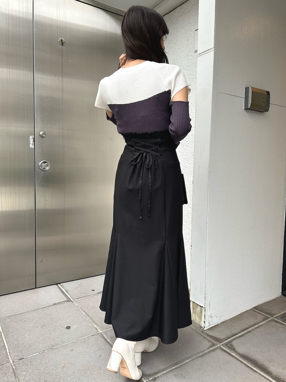 グレー系のニット/セーター、ブラック系のスカート、ブラック系のショルダーバッグを着用したレディースの冬コーディネートの5枚目の写真