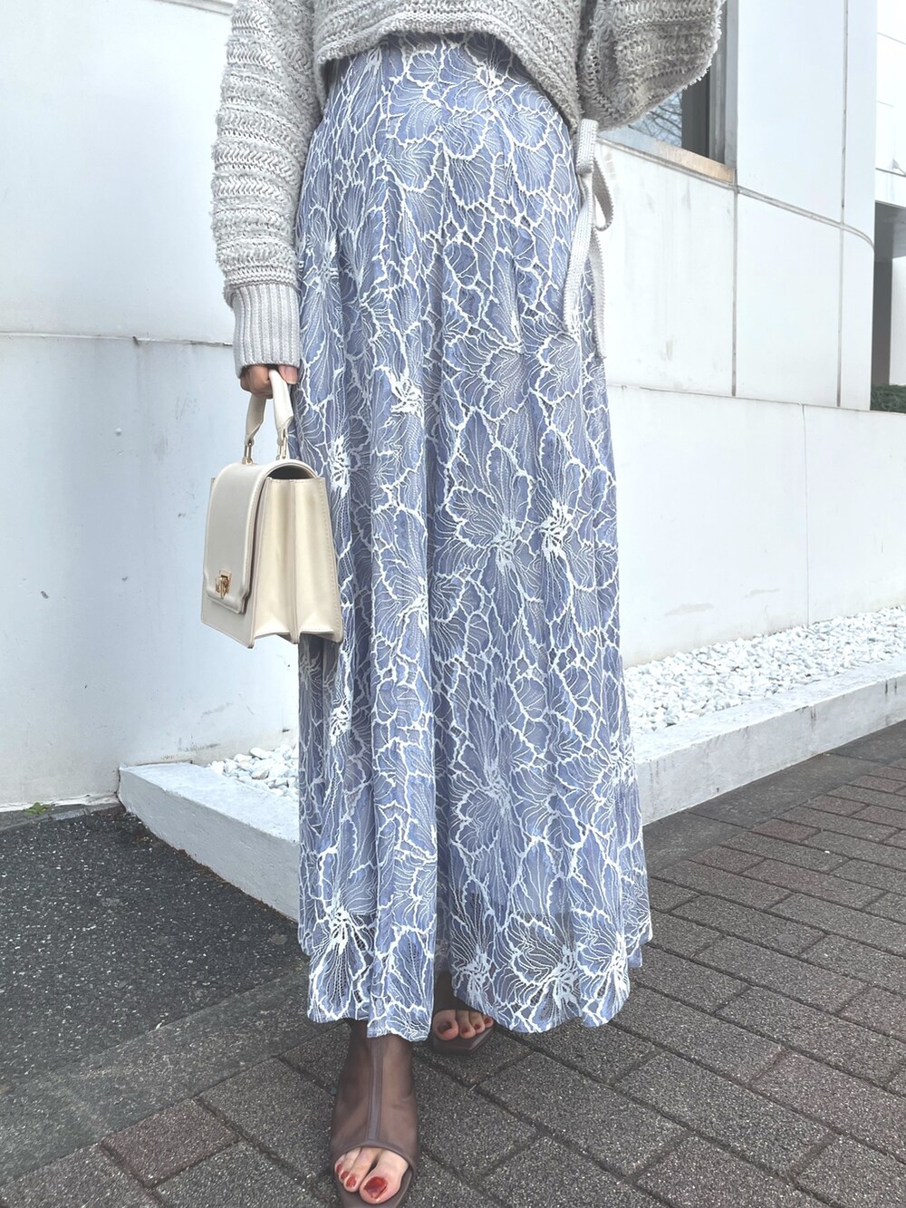 グレー系のニット/セーター、ブルー系のスカート、ホワイト系のハンドバッグを着用したレディースの冬コーディネートの4枚目の写真