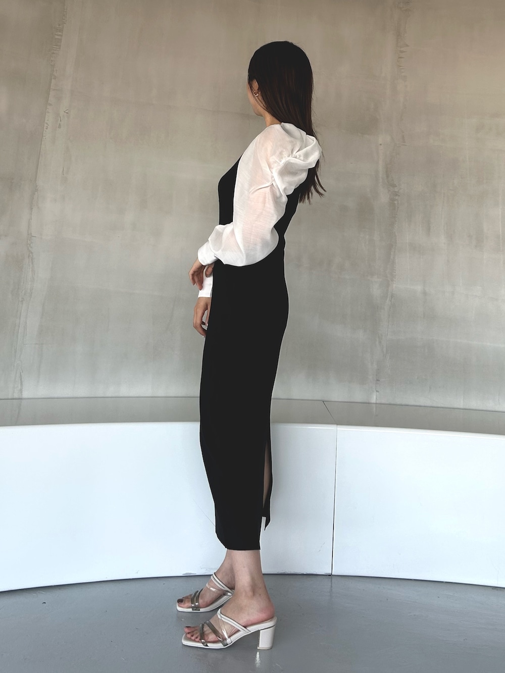 ブラック系のワンピース、ホワイト系のサンダルを着用したレディースの冬コーディネートの2枚目の写真