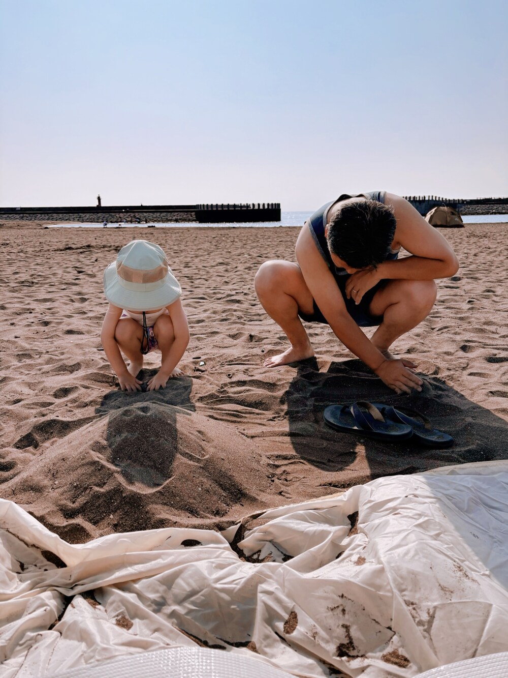 ピンク系の水着、パープル系のラッシュガード、グリーン系のハットを着用したキッズの夏コーディネートの5枚目の写真