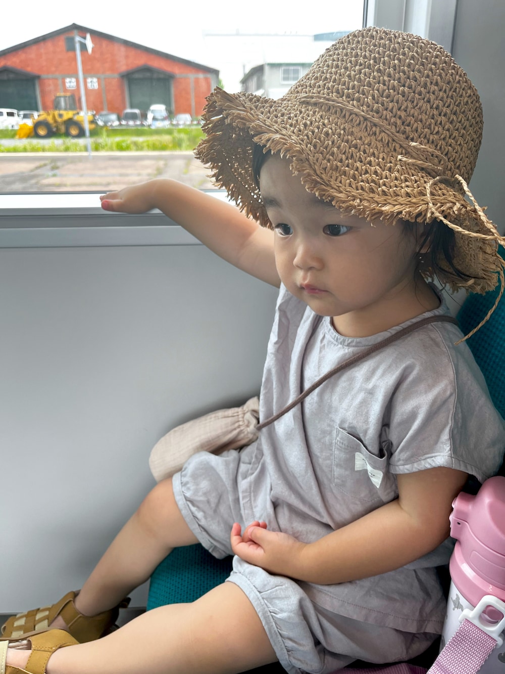 グレー系のセットアップ、ベージュ系のバッグ、ベージュ系の帽子を着用したキッズの夏コーディネートの2枚目の写真