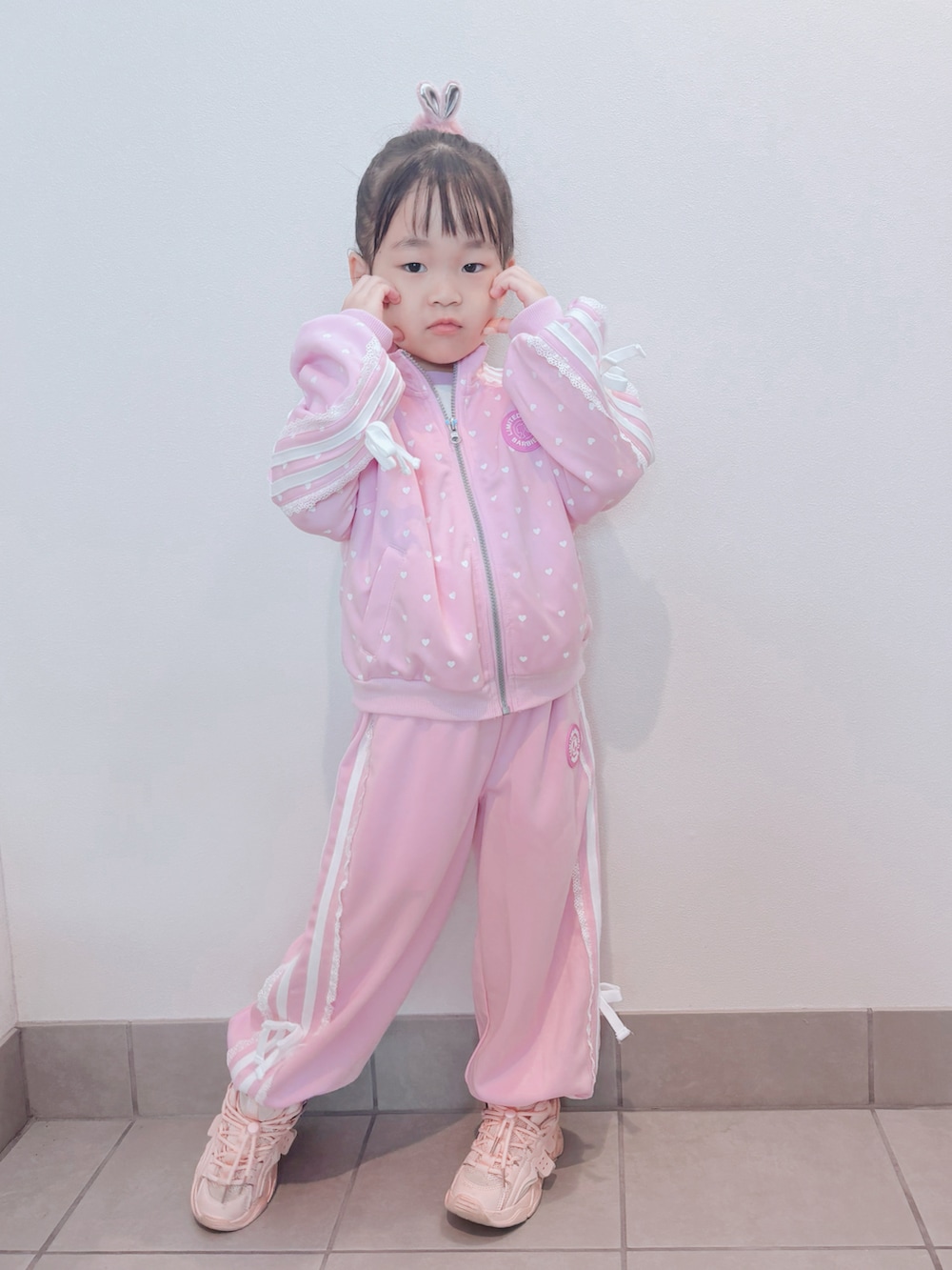 ピンク系のセットアップ、ピンク系のパンツ、ピンク系のスニーカーを着用したキッズの秋コーディネートの2枚目の写真